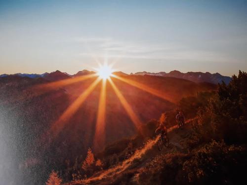 two people riding bikes on a hill with the sun shining at Haus Silvia in Flachau