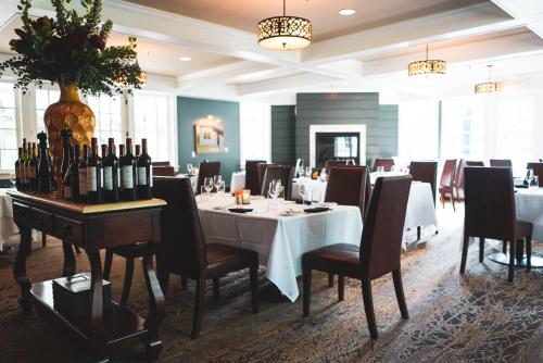 Reluctant Panther Inn & Restaurant في مانشستر: غرفة طعام مع طاولة مع زجاجات من النبيذ