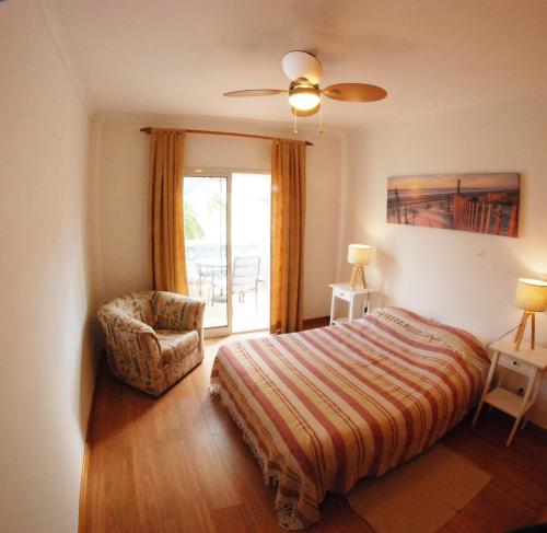 ポルト・サントにあるPorto Santo Serenity Beach Houseのベッドルーム1室(ベッド1台、椅子、窓付)
