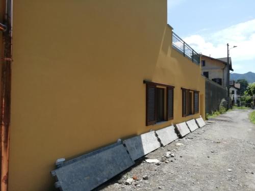 a yellow building with black shutters on a street at La casa di Beppe c cir D1135 in Lanzo dʼIntelvi