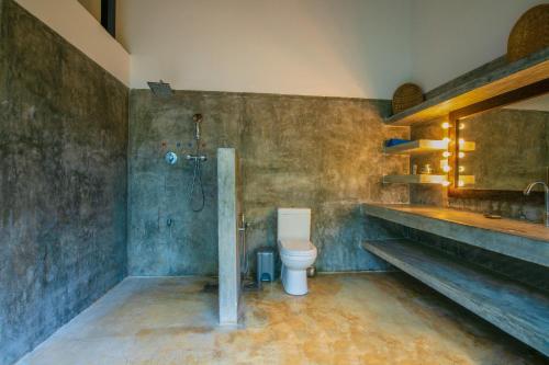 uma casa de banho com um WC, um chuveiro e um lavatório. em Gangananda em Ambalangoda