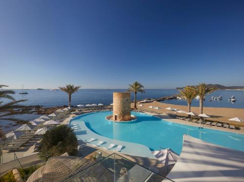 una piscina con sombrillas y una playa en Hotel Torre del Mar - Ibiza en Playa d'en Bossa