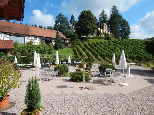 a patio with tables and chairs and white umbrellas at Wein Lodge Durbach - Gruppenhaus Weingut Neveu in Durbach