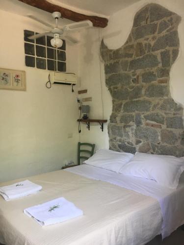 a bed in a room with a stone wall at S'Imbragu Farm B&B in Tortolì