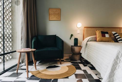a bedroom with a green chair and a bed at Casa Ixaya by Barrio México in Guadalajara