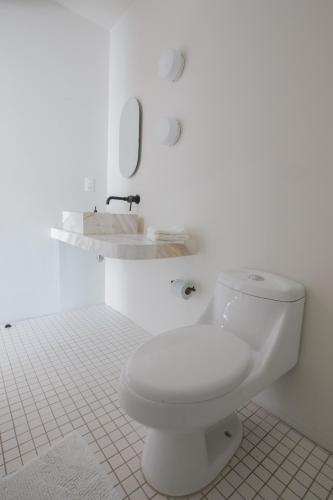 a white bathroom with a toilet and a sink at Casa Ixaya by Barrio México in Guadalajara