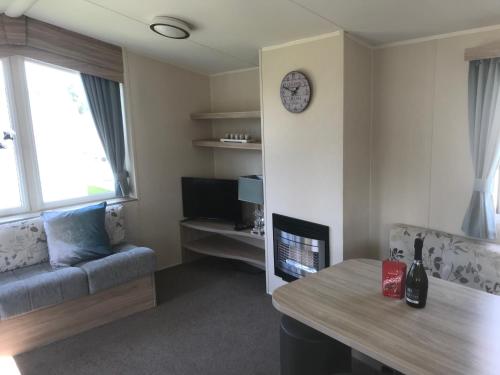 a living room with a couch and a clock on the wall at 3 bedroom deluxe caravan in Longniddry