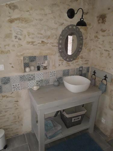 une salle de bain avec un lavabo et un miroir au mur dans l'établissement l' Oiseau Bleu, à Bazoges-en-Pareds