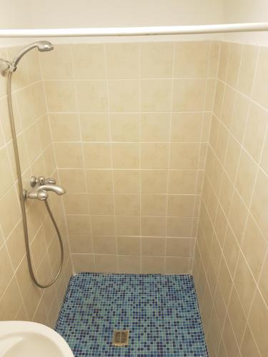 a bathroom with a shower with a toilet and a blue tile floor at TRIANON Hostel - Central Paphos Old Town in Paphos City