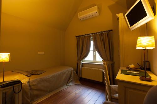 a bedroom with a bed and a desk and a window at Hotel Boterhuis in Bruges