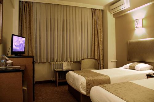 a hotel room with two beds and a television at Hotel Artiç in Bursa