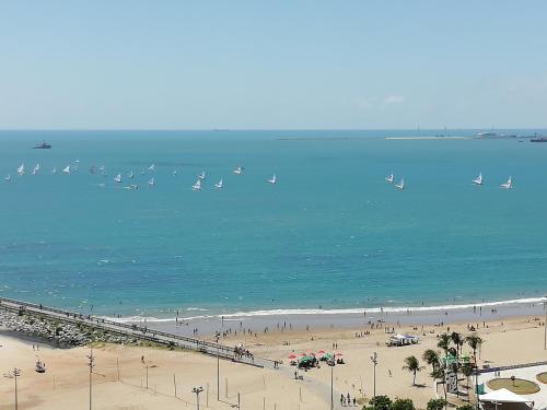 a beach with people and boats in the water at Beach Class Rosalux 707 in Fortaleza