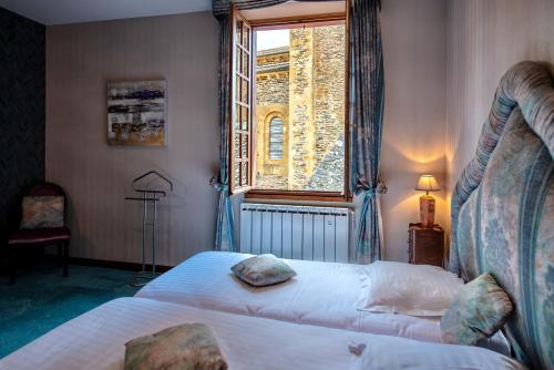 sypialnia z 2 łóżkami i oknem w obiekcie Hôtel Sainte Foy w mieście Conques