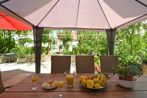 una mesa con platos de fruta y vasos de zumo de naranja en Apartments Petra, en Marina