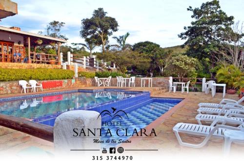 una piscina en un hotel con sillas blancas alrededor en Hotel boutique Santa Clara Mesa de los Santos, en Los Santos