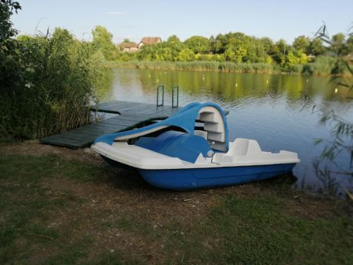 a blue and white boat on the shore of a lake at OAZA KUĆA ZA ODMOR in Čurug