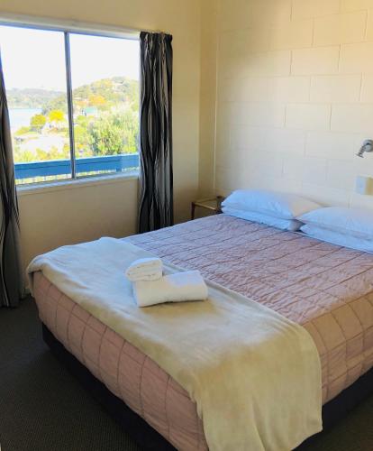a bedroom with a large bed with two towels on it at Waiheke Island Motel in Ostend