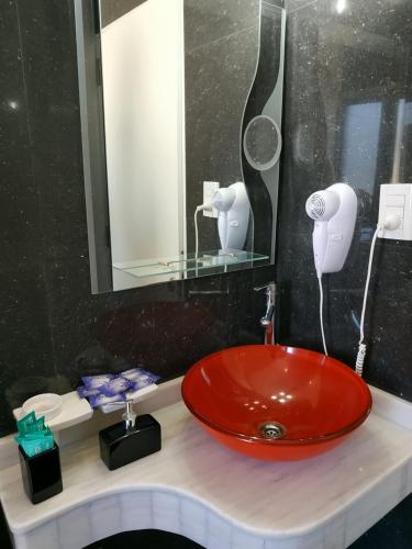 baño con lavabo rojo y espejo en Complejo Cortazar Rafaela en Rafaela