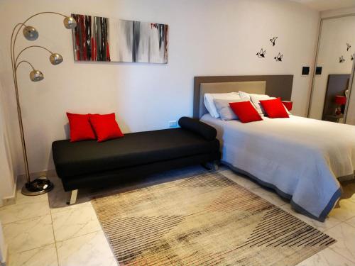 1 dormitorio con cama con almohadas rojas y sofá en Complejo Cortazar Rafaela en Rafaela