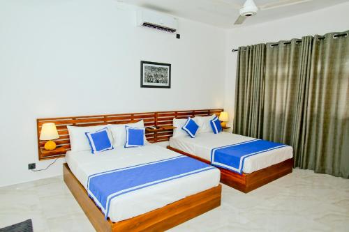 a bedroom with two beds with blue pillows at Sapumal Lodge in Anuradhapura