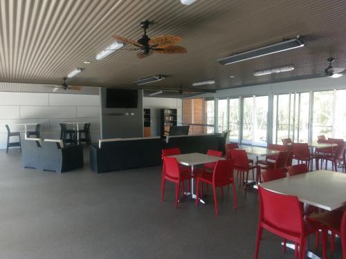 a dining room with tables and red chairs at Tuncurry Lakes Resort in Tuncurry