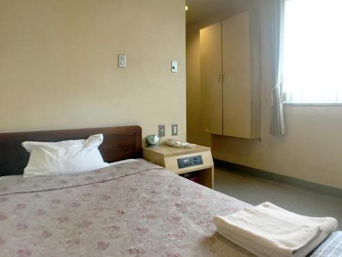 a bedroom with a bed and a nightstand and a window at Hotel Shibukawa Hills in Shibukawa