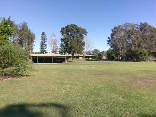a large grassy field with a house at Tuncurry Lakes Resort in Tuncurry