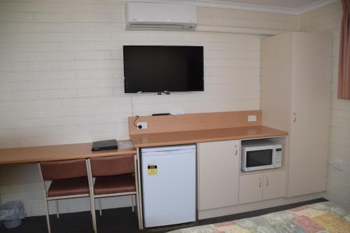 a room with a refrigerator and a tv on a wall at Big River Motel in Echuca