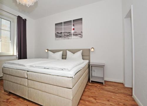 a bedroom with a large bed with white sheets at Haus Usedom Appartement MeeresSpiegel in Ostseebad Koserow