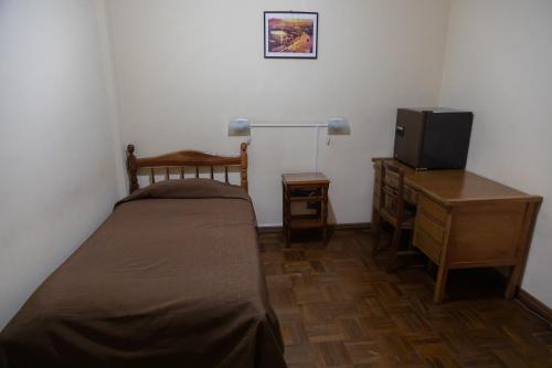 a small bedroom with a bed and a television at Julia Plaza Hotel in Uyuni