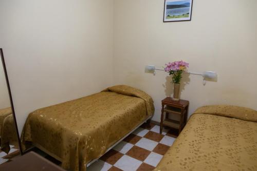 a room with two beds and a vase of flowers at Julia Plaza Hotel in Uyuni