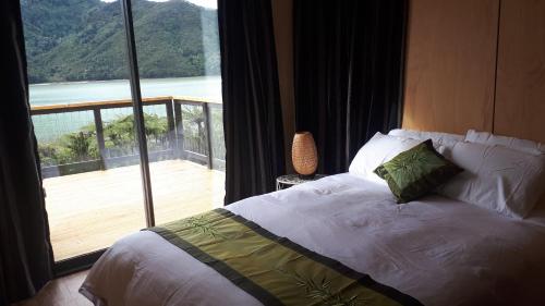 a bedroom with a bed with a view of a balcony at Marlborough Sounds Accommodation in Havelock