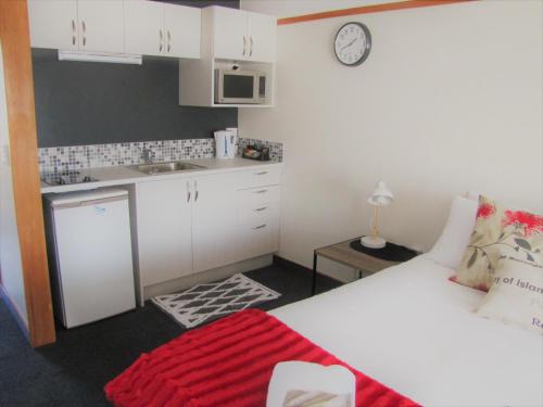 a bedroom with a white bed and a kitchen at The Beachcomber Hotel in Nelson