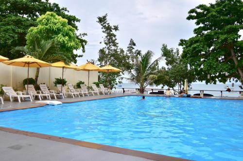 a large blue swimming pool with chairs and umbrellas at Vongdeuan Resort in Ko Samed