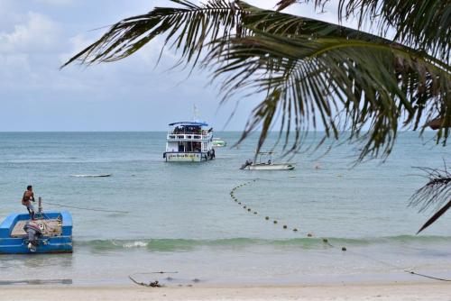 two boats in the water on a beach with a palm tree at Vongdeuan Resort in Ko Samed