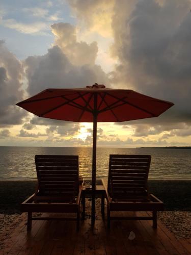 two chairs and a table with an umbrella on the beach at Sunari Beach Resort 2 in Selayar