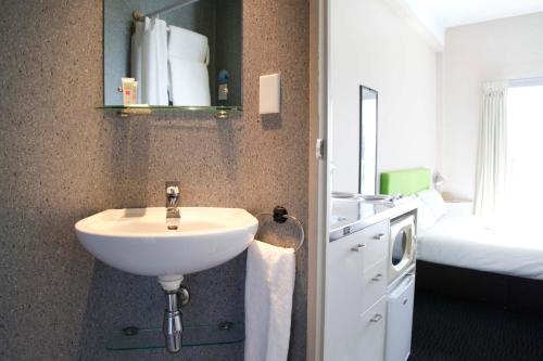 uma casa de banho com um lavatório branco e uma cama em ibis budget Auckland Central em Auckland