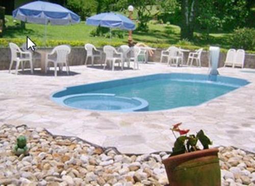 a swimming pool with chairs and a table and a table and chairs at Pousada Lua e Sol in Santo Antônio do Pinhal