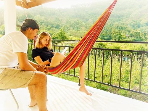a man and woman sitting in a hammock on a balcony at Ella Peace Heaven in Ella
