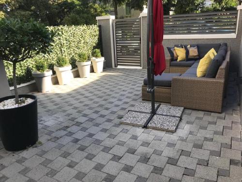 a patio with a couch and some plants and an umbrella at Holiday Home Aspalathos - with free parking, near the beach, a few minutes' walking distance to the UNESCO Palace in Split