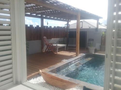 a pool with a wooden deck with a wooden boat in it at Maison TONGA piscine jaccuzi in Saint-Pierre