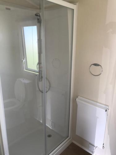 a white bathroom with a shower and a toilet at 3 bedroom deluxe caravan in Longniddry