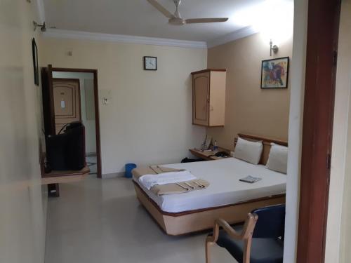 a room with a bed and a tv in it at Hotel Jay International in Vapi