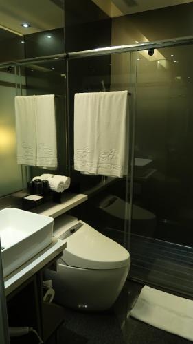 a bathroom with a toilet and a shower with towels at Amici hotel Six Star Hostel in Taipei