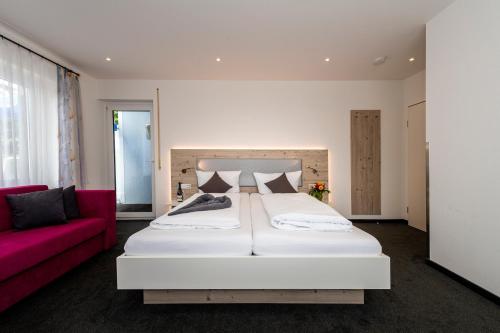 1 dormitorio con 1 cama blanca grande y 1 sofá rojo en Gästehaus Holzer, en Constanza
