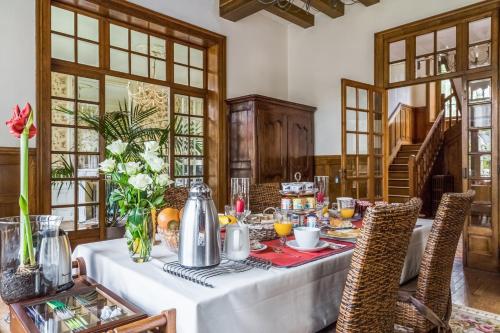 a dining room with a table with food and flowers at La Maison Rouge Brocéliande in Montauban-de-Bretagne
