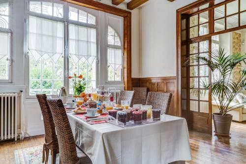 a dining room with a white table and chairs at La Maison Rouge Brocéliande in Montauban-de-Bretagne