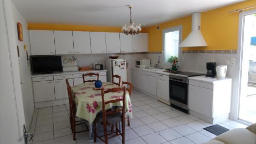 una cocina con armarios blancos y una mesa con sillas. en Appartement en rez de chaussee de maison en Espelette