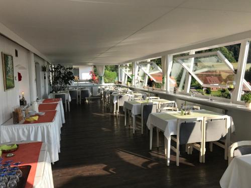 un restaurant avec des tables blanches, des chaises blanches et des fenêtres dans l'établissement Hotel-Berggasthof Schwarzwaldperle, à Sasbachwalden