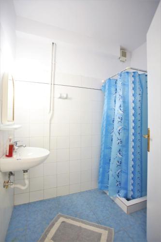 a bathroom with a blue shower curtain and a sink at Pension Ioanna in Adamantas